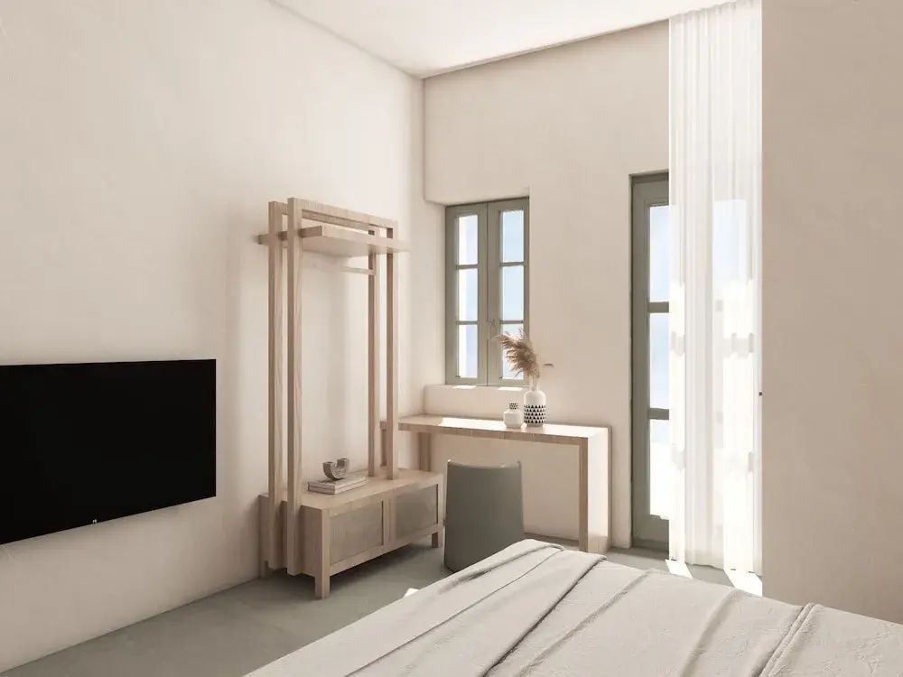 Hell eingerichtetes Schlafzimmer mit Holzgarderobe, Schreibtisch und Wandfernseher.