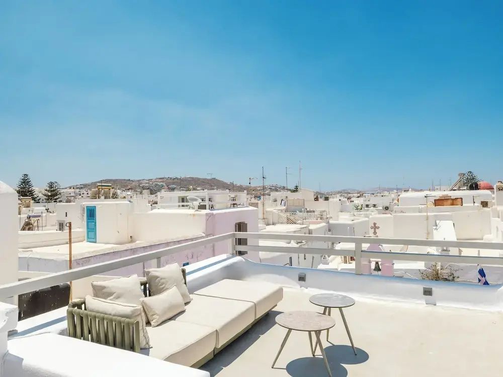 Dachterrasse mit Sitzecke und Blick über die weißen Häuser der Stadt unter blauem Himmel.