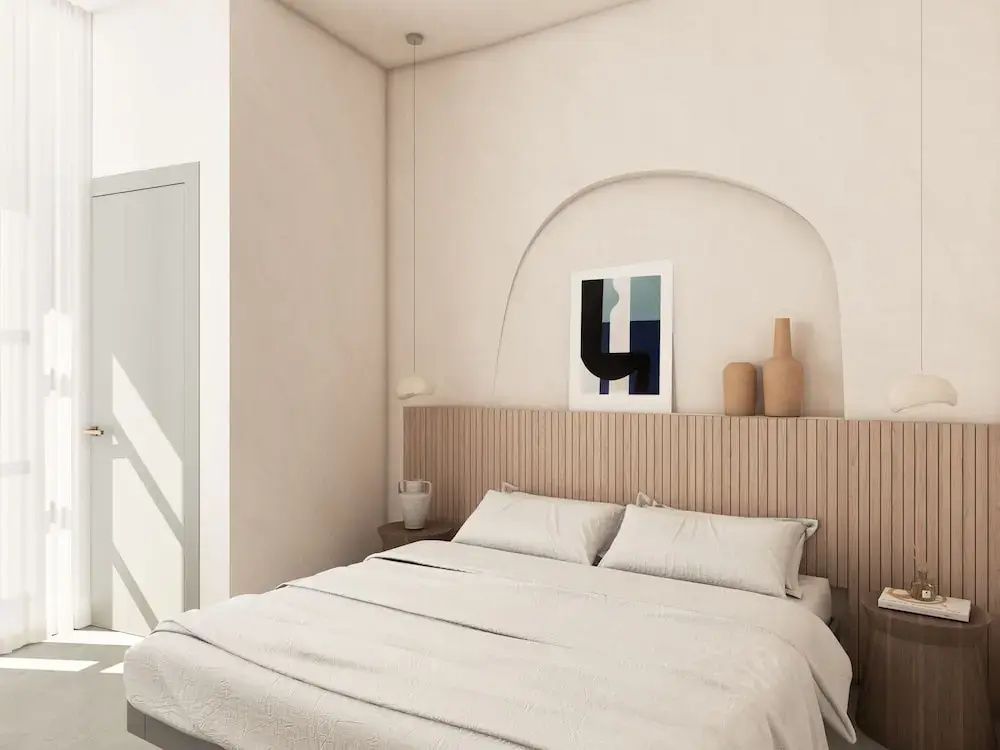 Schlafzimmer mit beige gestalteter Wand, Rundbogennische und Holzkopfteil am Bett.