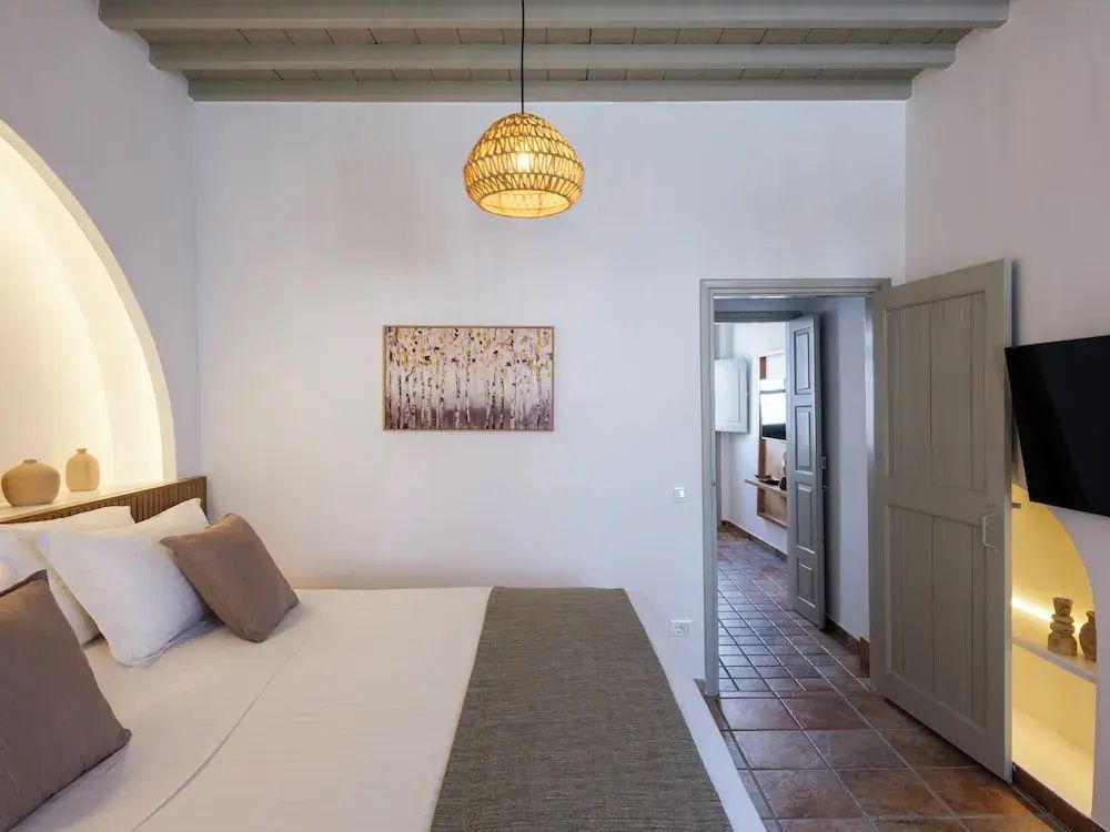 Schlafzimmer mit Doppelbett, Flechtlampe an der Holzdecke und Wandbild.