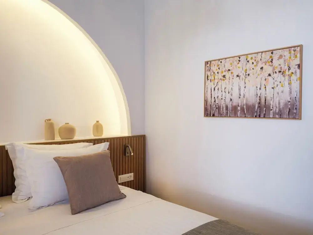Doppelbett mit beleuchteter Wandnische, kleinen Vasen und einem Wandbild.