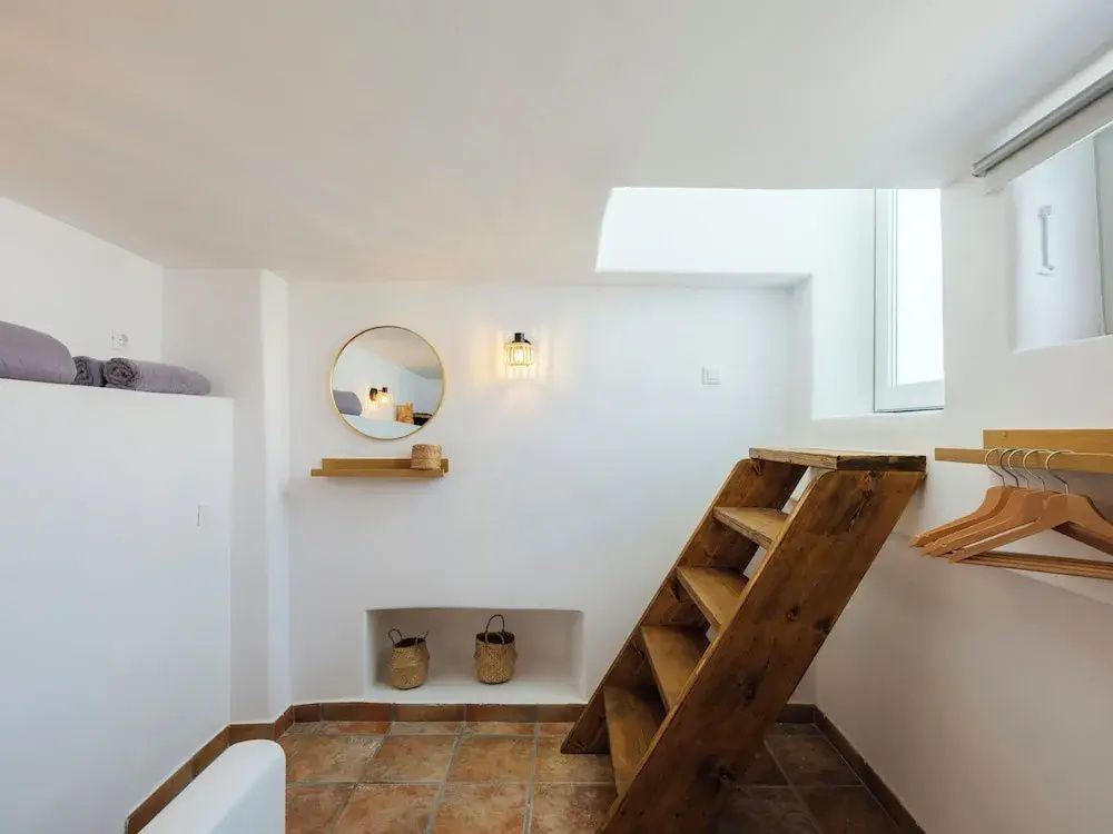 Zimmer mit einer Holztreppe, rundem Wandspiegel und Nischen im traditionellen Stil.