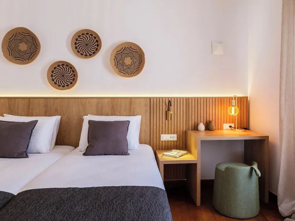 Schlafbereich mit Betten, Holzpaneelen an der Wand, kleiner Schreibecke und Wanddekoration.