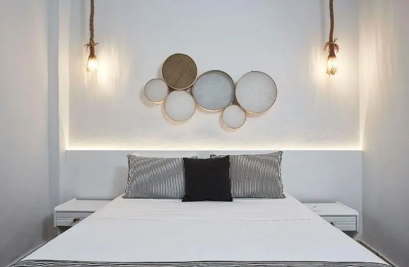 Doppelbett mit Kissen und beleuchteter Wanddekoration aus mehreren runden Elementen.