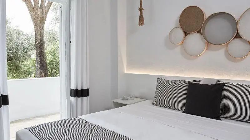 Hell eingerichtetes Schlafzimmer mit Doppelbett und Kissen in Weiß und Grau.