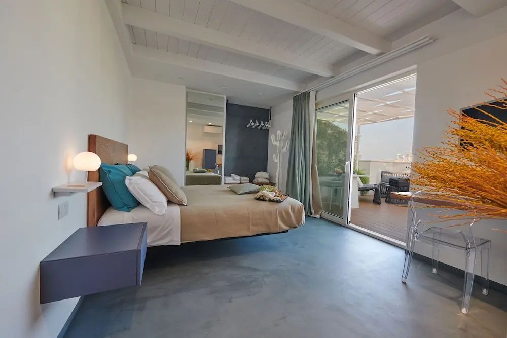 Modernes Hotelzimmer mit Doppelbett, Kissen und Zugang zur Terrasse.