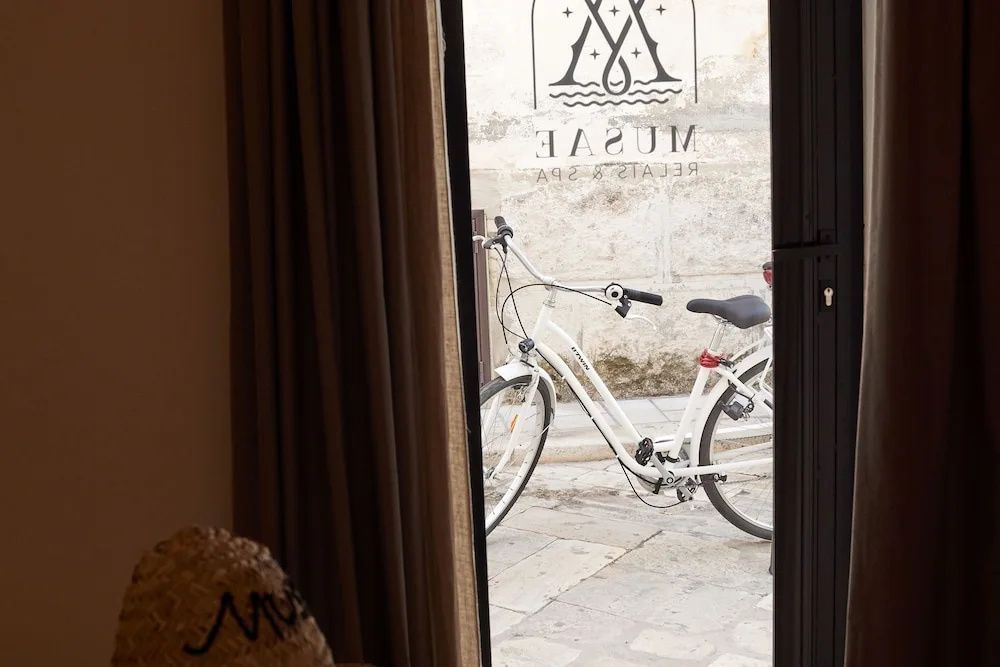 Blick durch ein Fenster mit Aufschrift auf ein weißes Fahrrad in der Gasse.