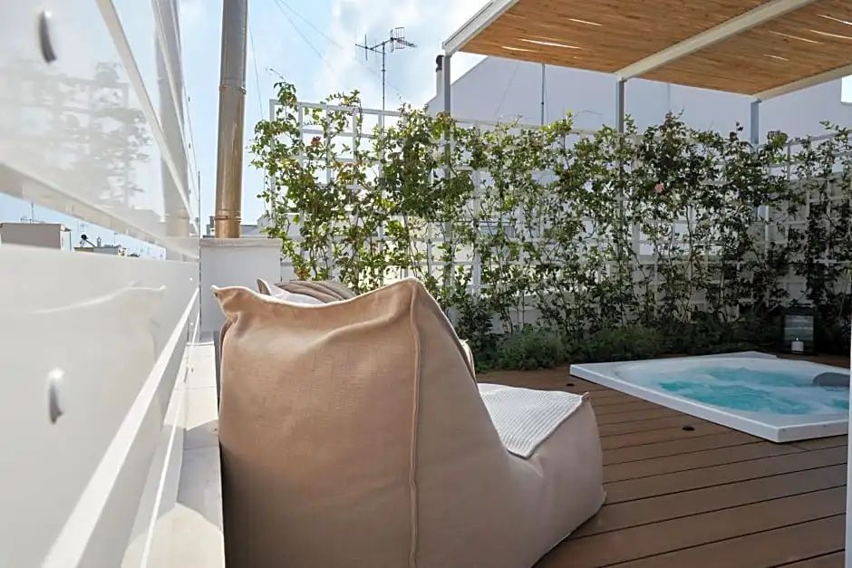 Bodenkissen auf einer sonnigen Terrasse mit Holzboden und bepflanzter Gitterwand.