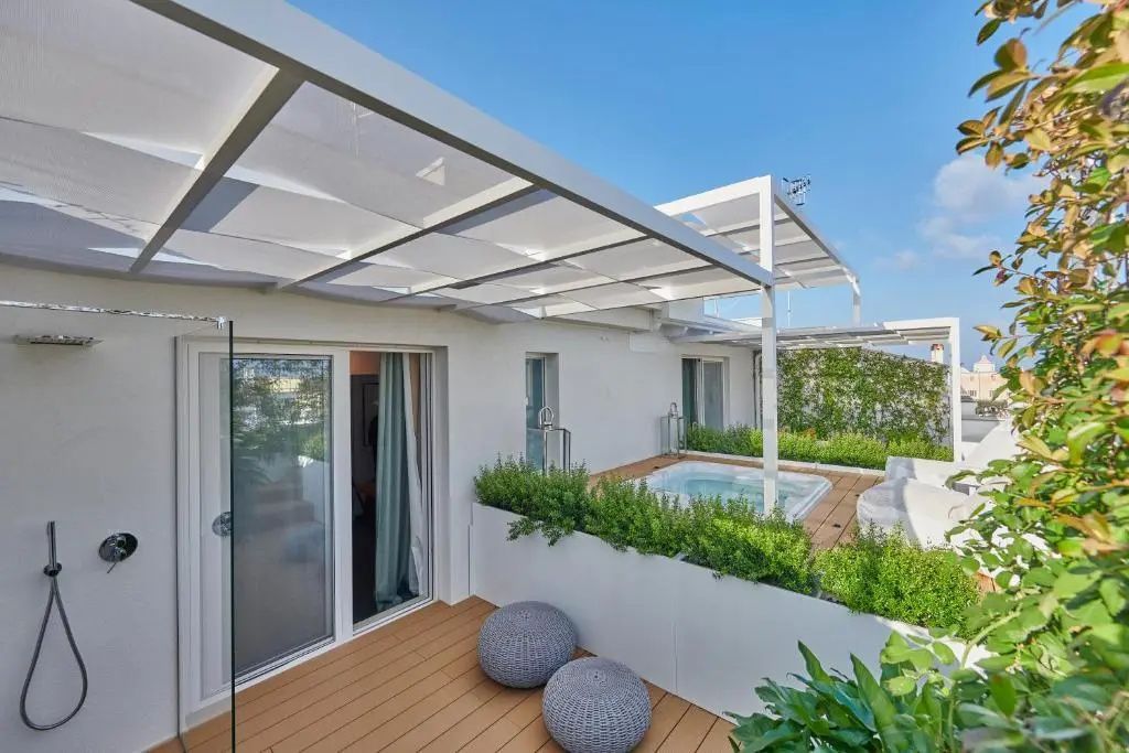 Moderne Dachterrasse mit Holzbelag, Whirlpool, Pflanzen und weißer Überdachung.