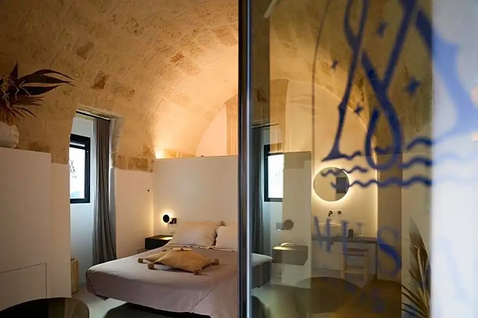 Blick durch eine Glasscheibe in ein Hotelzimmer mit Steingewölbe und Doppelbett.