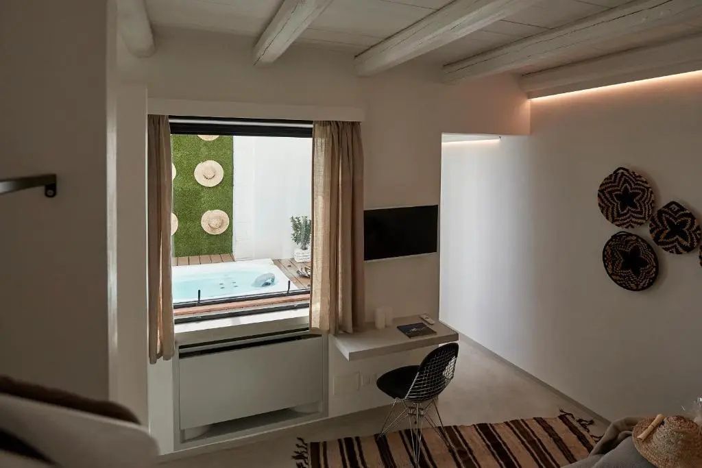 Blick durch ein Innenfenster auf eine Terrasse mit einem Whirlpool draußen.