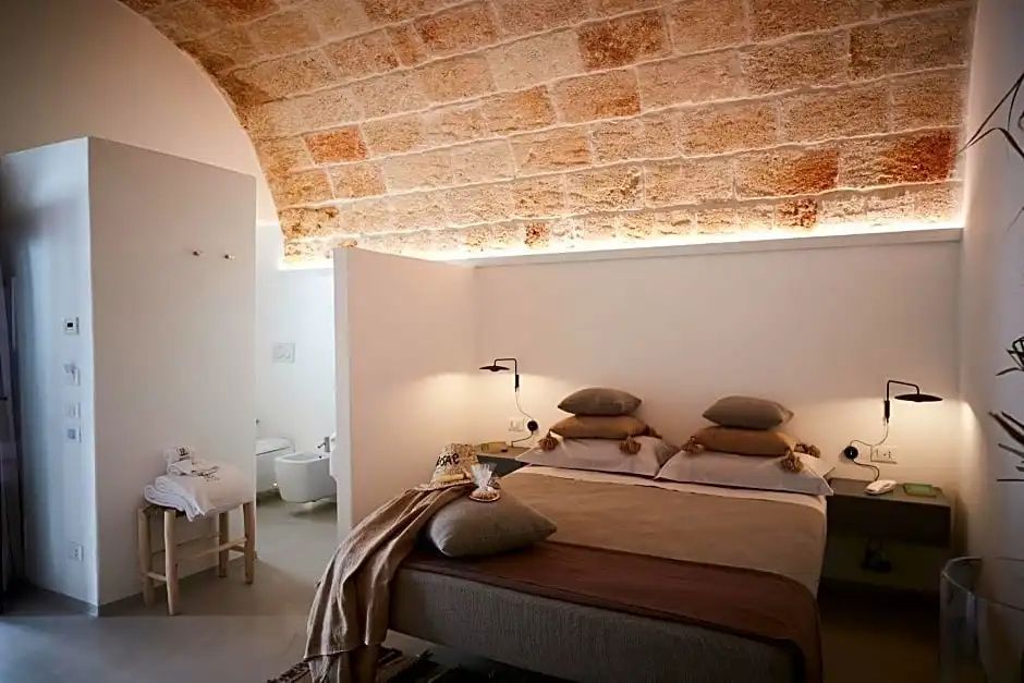 Hotelzimmer mit einer Decke aus Natursteingewölbe und beige dekoriertem Doppelbett.
