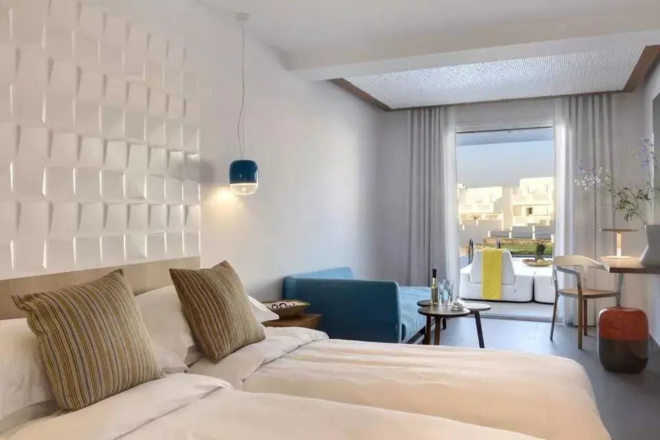 Blick durch ein helles Zimmer auf die angrenzende Terrasse mit Liegemöglichkeiten.