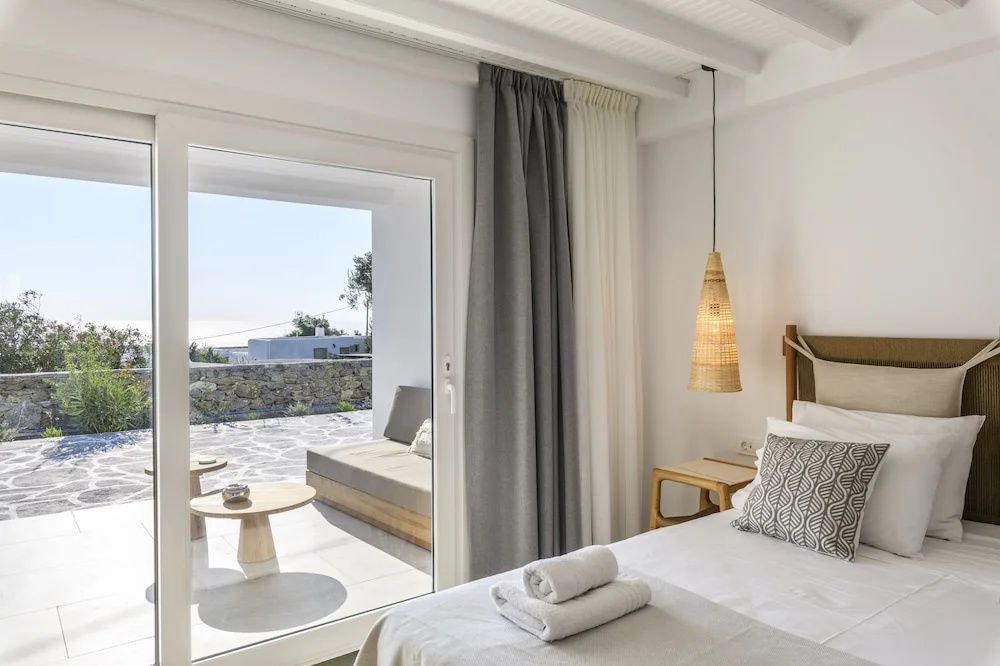 Blick aus dem Schlafzimmer auf die Terrasse mit Sitzgelegenheiten.