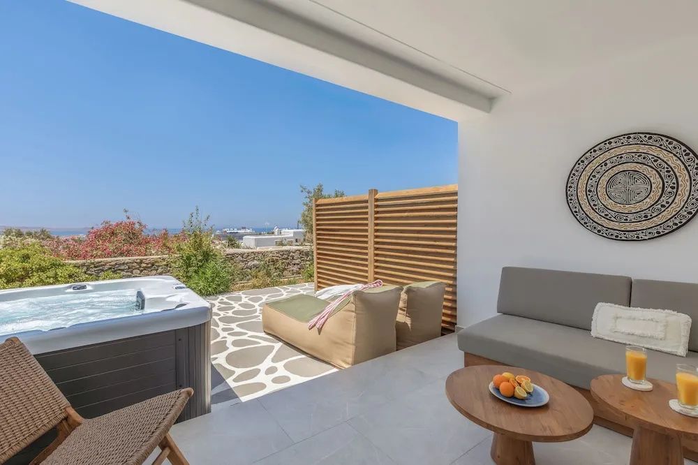 Überdachte Terrasse mit Whirlpool, Liegestuhl und Ausblick auf das Meer.