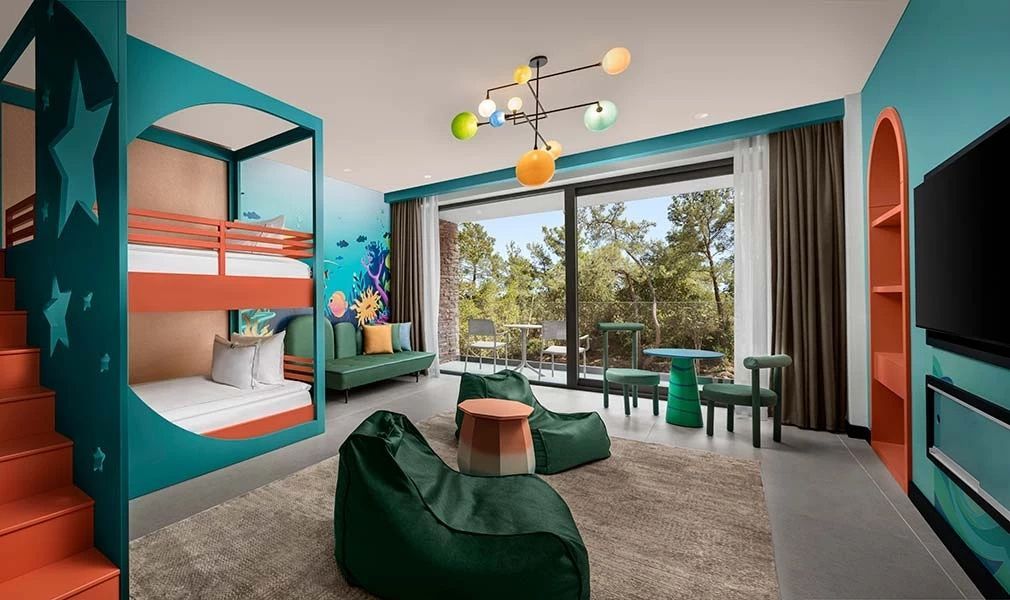 Kinderzimmer mit bunten Sitzmöbeln, Wandbild und Fensterfront zum Balkon.