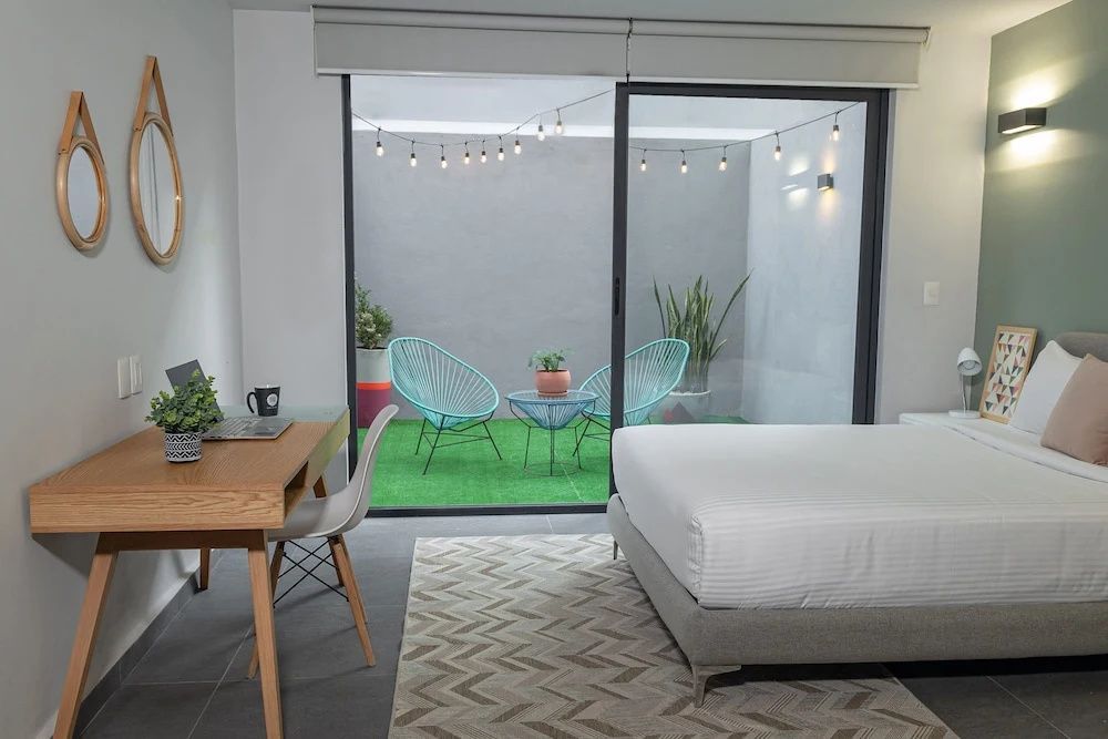 Hotelzimmer mit Doppelbett, Schreibtisch und Zugang zur Terrasse mit Sitzgelegenheiten.