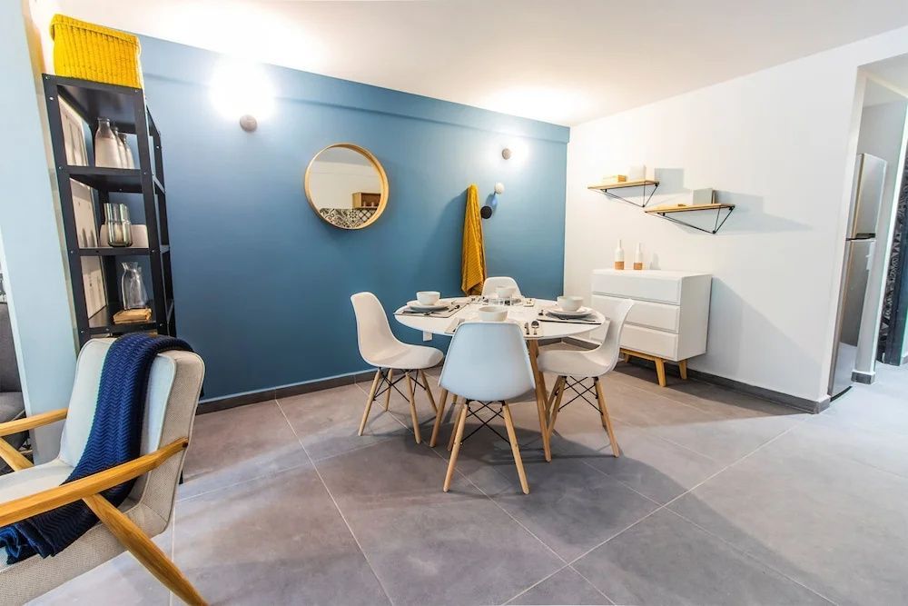 Runder Esstisch mit vier Stühlen vor einer blauen Wand in einem hellen Loft.
