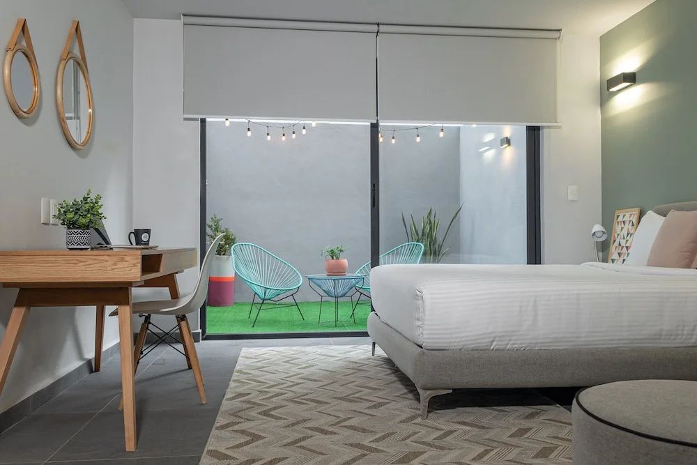 Modernes Hotelzimmer mit Doppelbett, Schreibtisch und Blick auf die Terrasse.