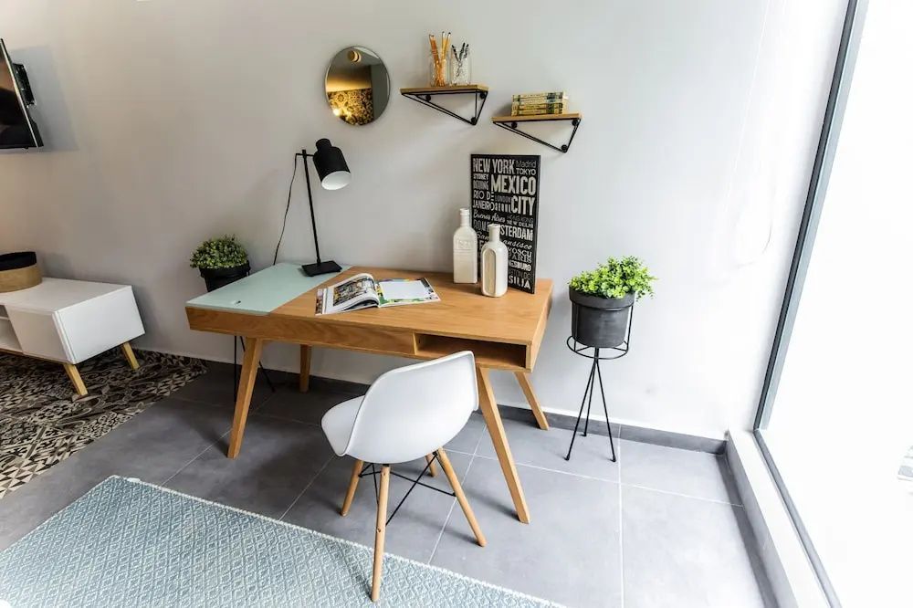 Moderne Arbeitecke mit Holztisch, weißem Stuhl, Tischlampe und Wanddekorationen.