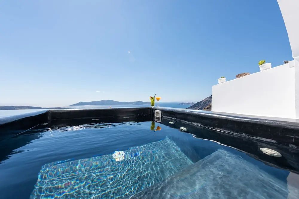 Ein kleiner Whirlpool auf der weißen Terrasse blickt auf das blaue Meer.