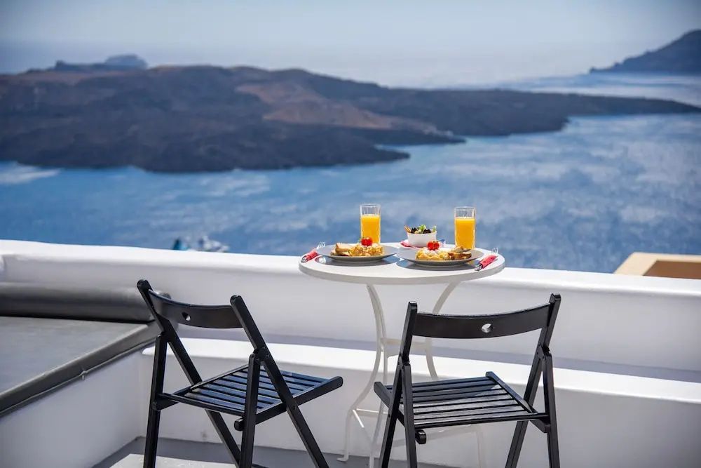 Frühstückstisch mit zwei Stühlen auf einer Terrasse mit Blick auf das Meer.