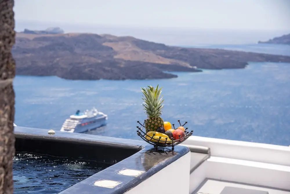 Obstschale am Rand eines Whirlpools mit Blick auf das Meer und ein Kreuzfahrtschiff.