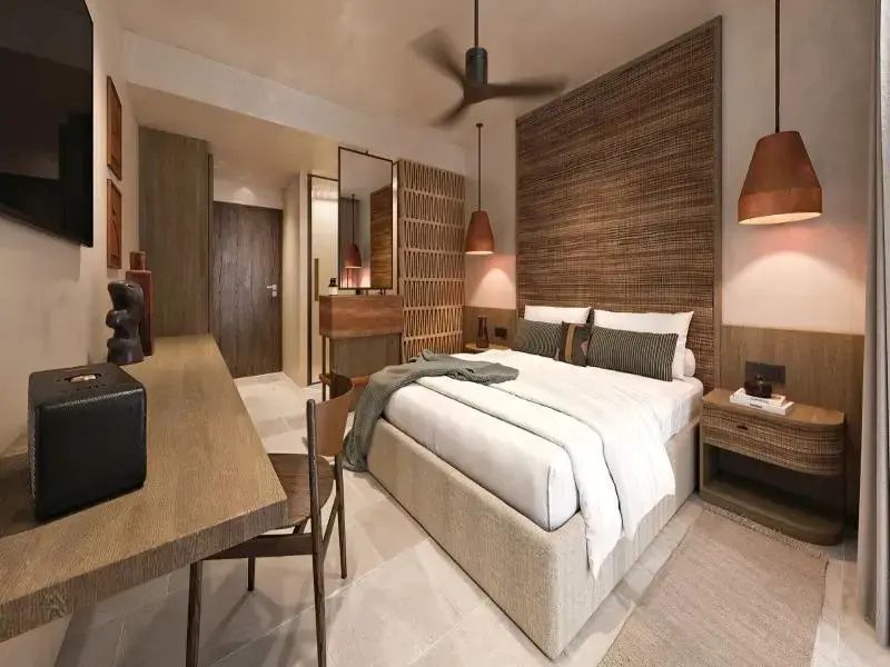Einrichtung eines Hotelzimmers mit Holzrückwand, Bett, Deckenventilator und Schreibtisch.