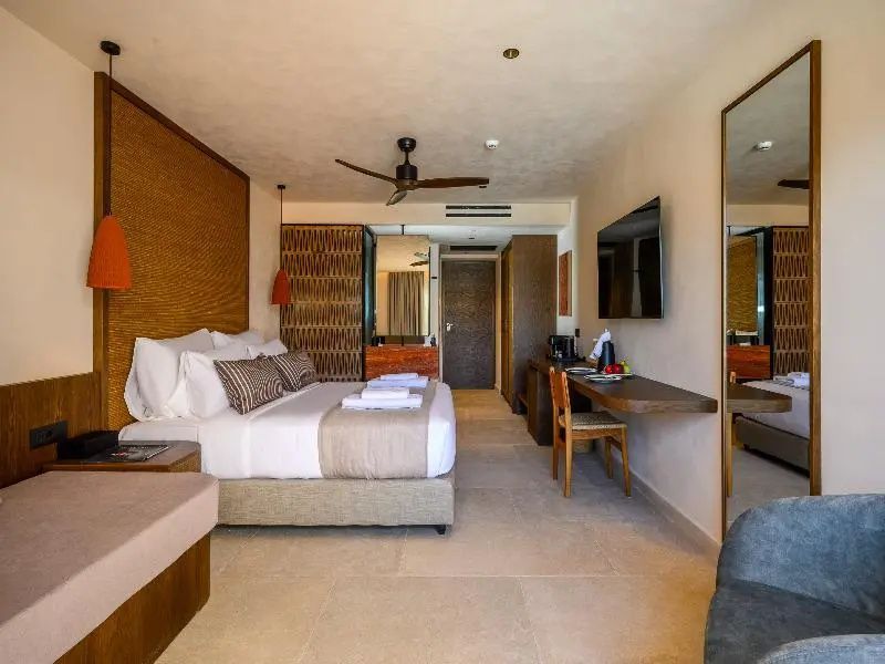 Geräumiges Hotelzimmer mit Doppelbett, Fernseher an der Wand und großem Wandspiegel.