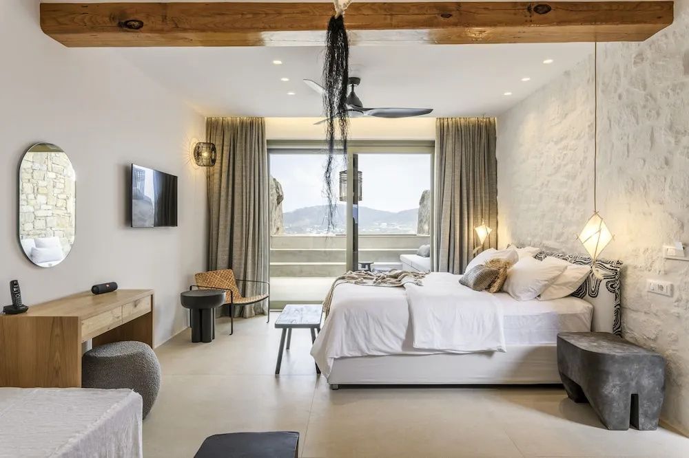 Hell eingerichtetes Schlafzimmer mit Doppelbett, Deckenventilator und Balkontür.