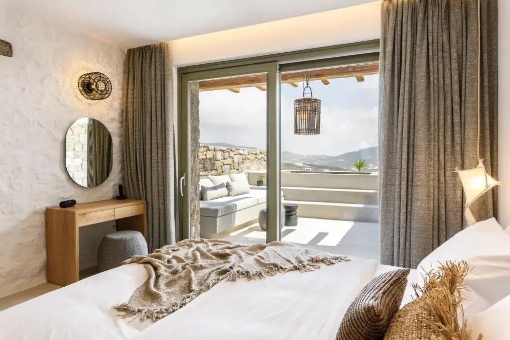 Blick aus dem Schlafzimmer durch eine Glasschiebetür auf die Terrasse und die Landschaft.