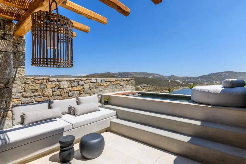 Möblierte Terrasse mit Sitzgelegenheiten, Stufen zum Pool und Blick auf die Landschaft.