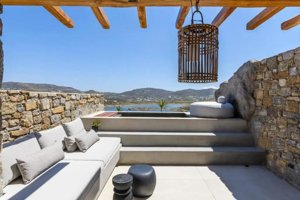 Sitzbereich auf der Terrasse mit Holzpergola, kleinem Pool und Blick auf die Landschaft.