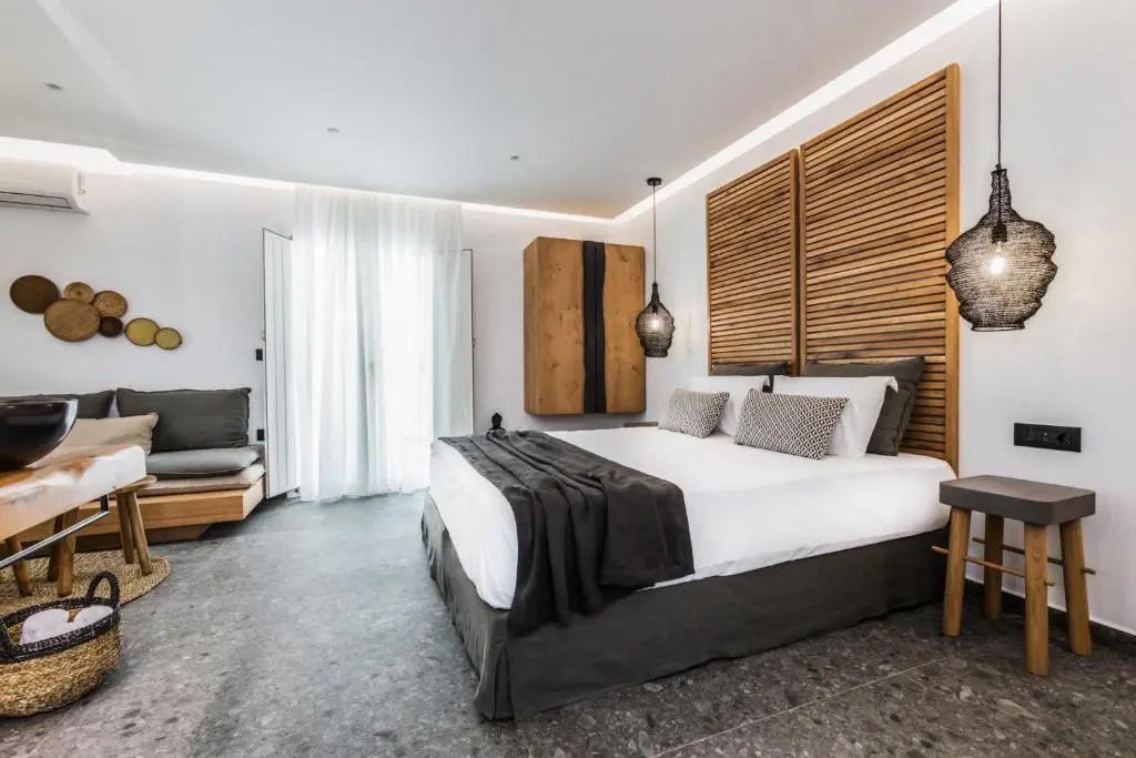 Modernes Hotelzimmer mit Doppelbett, Holzkopfteil und grauem Steinboden.