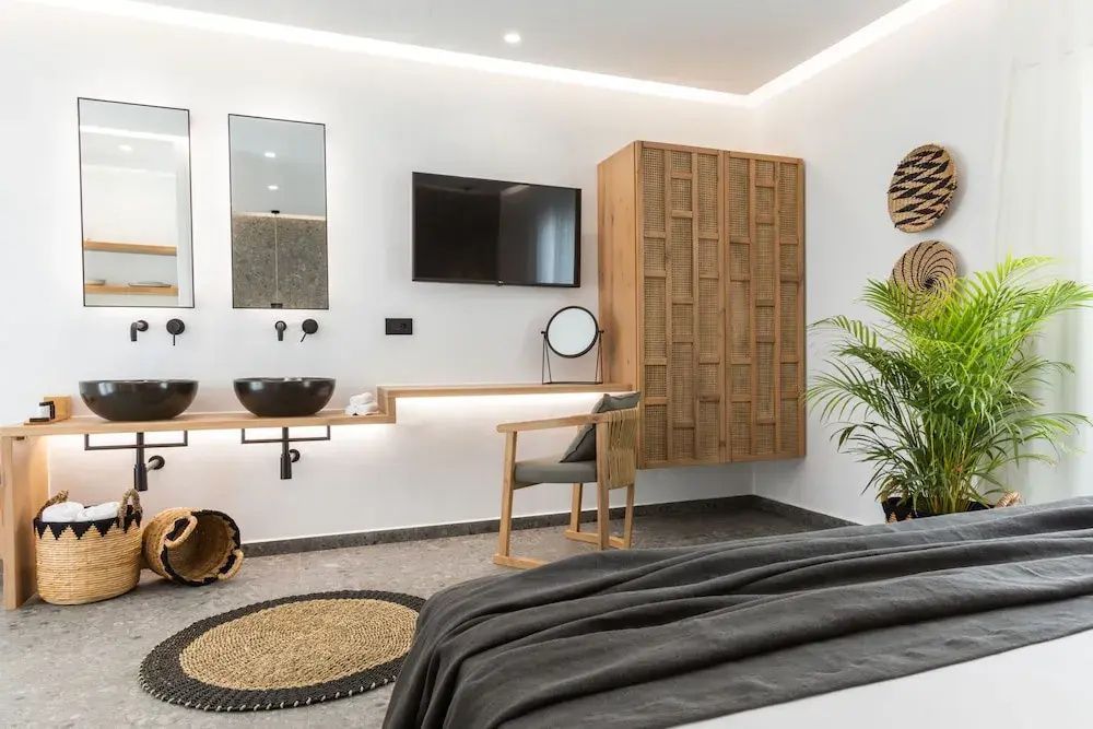 Zimmerbereich mit Holzschrank, Fernseher an der Wand und Doppelwaschbecken.