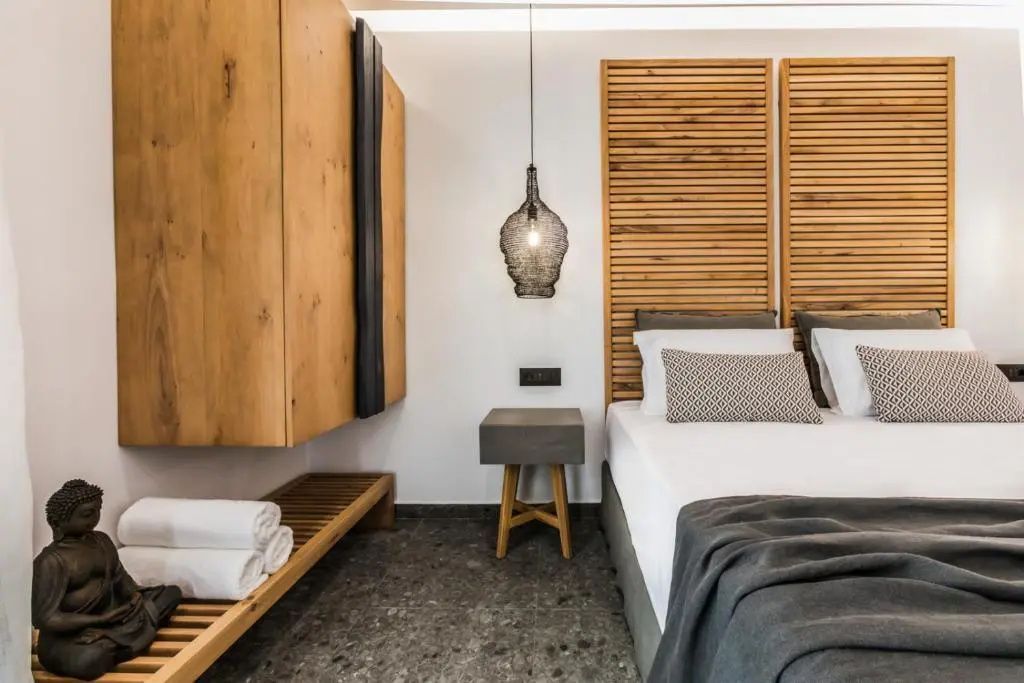 Doppelbett mit Kopfteil aus Holz, Nachttisch und Holzschrank im Hotelzimmer.