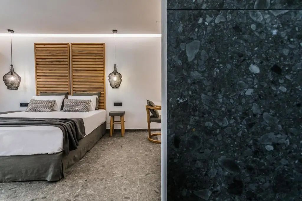 Seitenansicht des Schlafbereichs mit Bett und Holzstuhl hinter einer Wand.