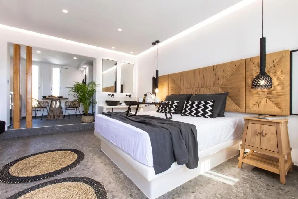 Helles Hotelzimmer mit großem Doppelbett, Flechtteppichen und offener Gestaltung.