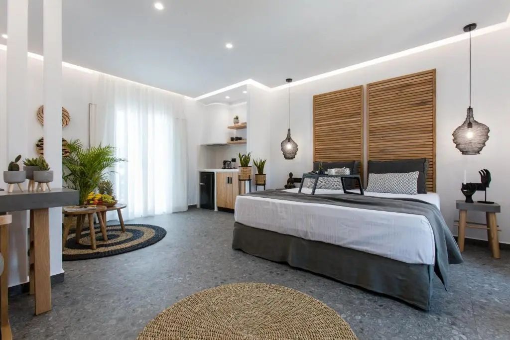 Helles Hotelzimmer mit großem Doppelbett, Holzdekoration an der Wand und Strohteppichen.