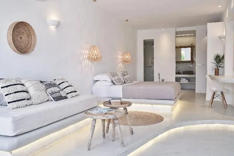 Helle Suite mit Sitzbereich, kleinen Holztischen, Doppelbett und angrenzendem Badezimmer.