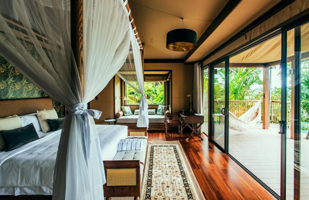 Schlafzimmer mit Holzboden, Himmelbett und Schiebetür zur Terrasse.