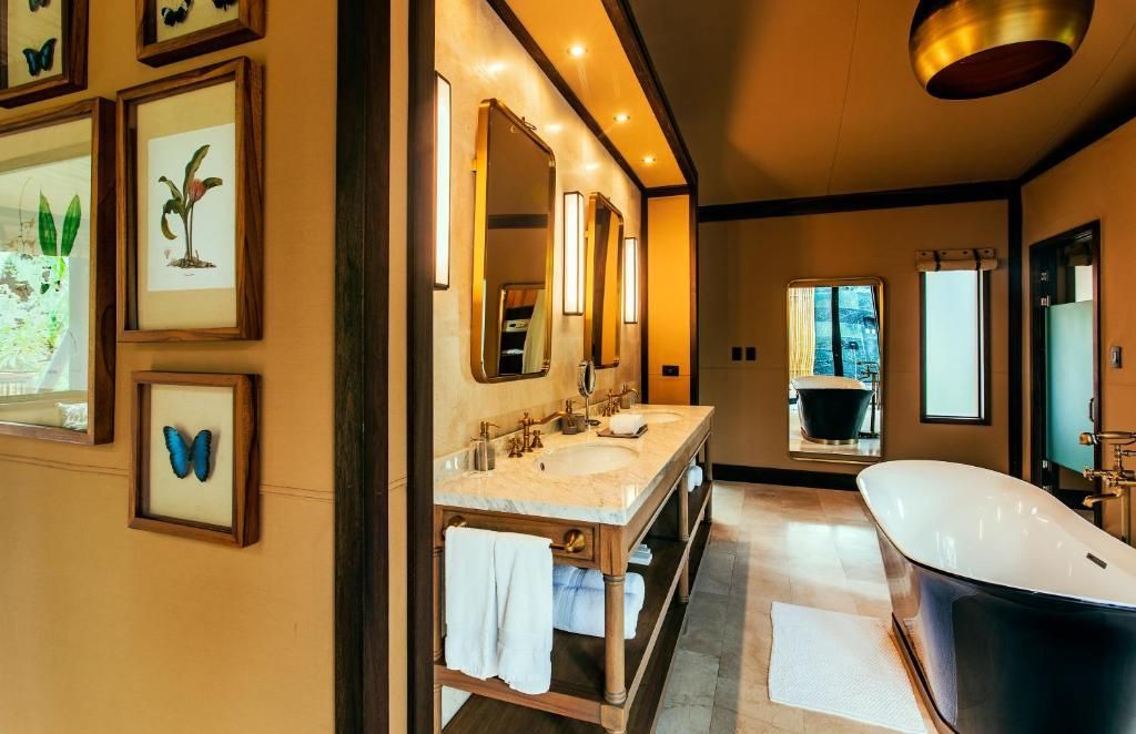 Badezimmer mit Doppelwaschtisch, beleuchteten Spiegeln und Holzschränken.
