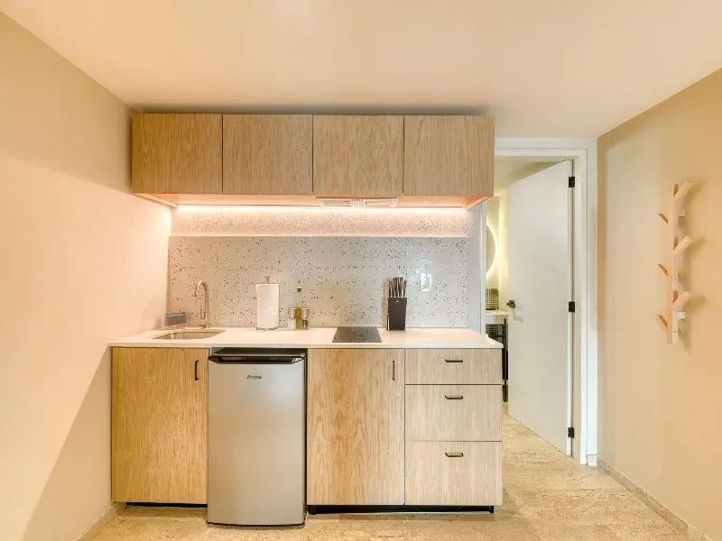 Frontale Ansicht der Küchenzeile aus hellem Holz mit Spüle und Kühlschrank.