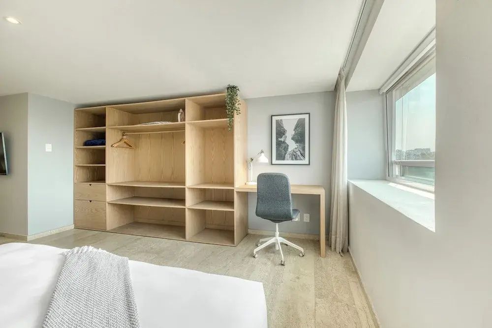 Offenes Holzregal und Schreibtisch mit Stuhl in einem hellen Zimmer.