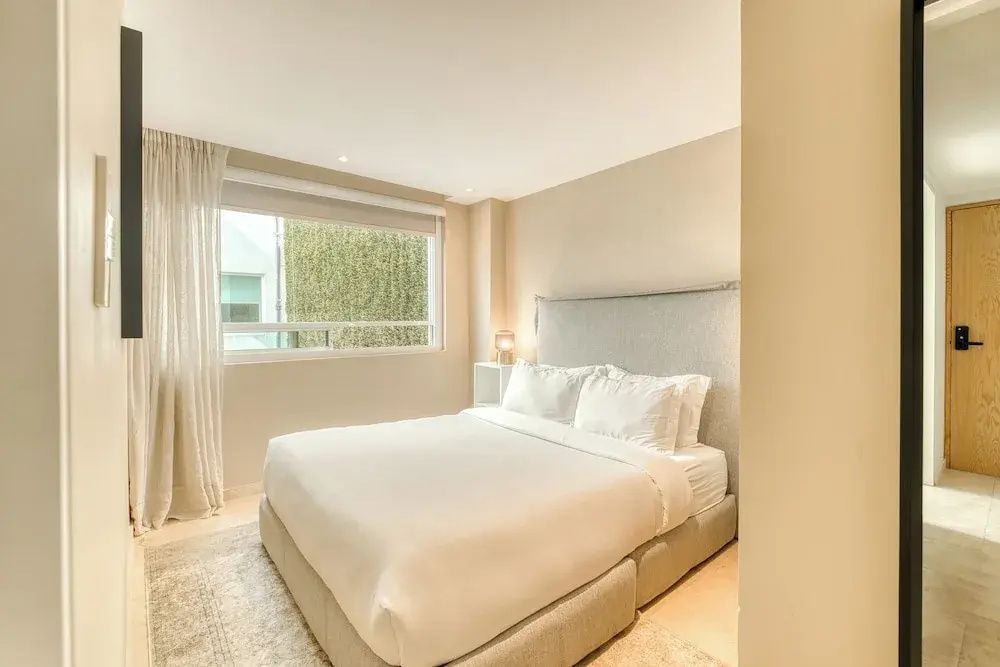 Helles Schlafzimmer mit großem Doppelbett und Fenster zur linken Seite.