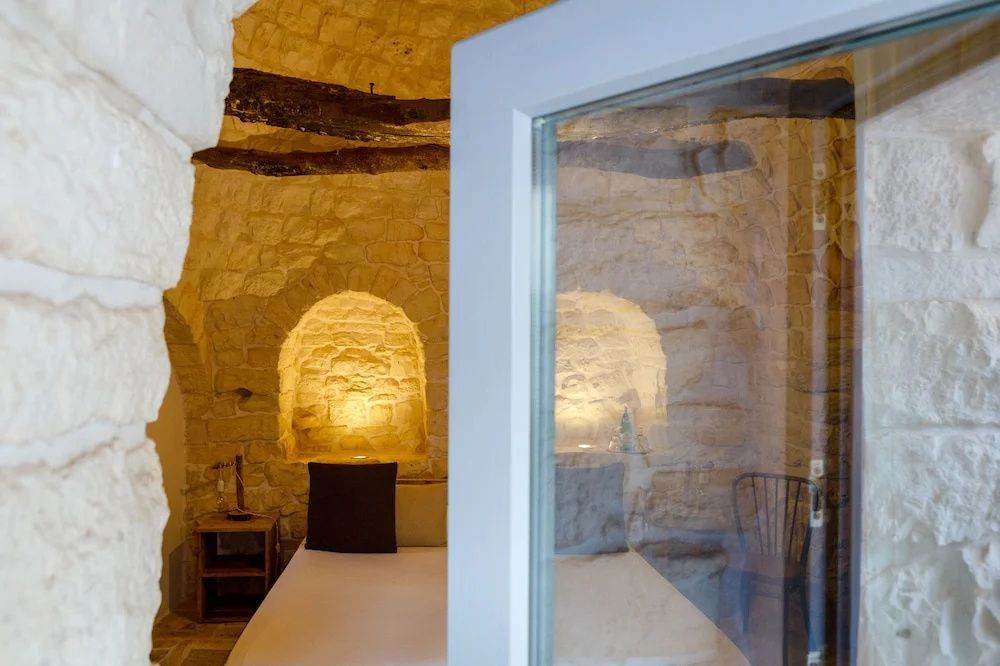 Blick durch eine geöffnete Tür in ein Schlafzimmer mit Natursteingewölbe.