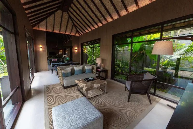 Wohnbereich einer Villa mit Sofa, Holztisch und großer Fensterfront zum Garten.