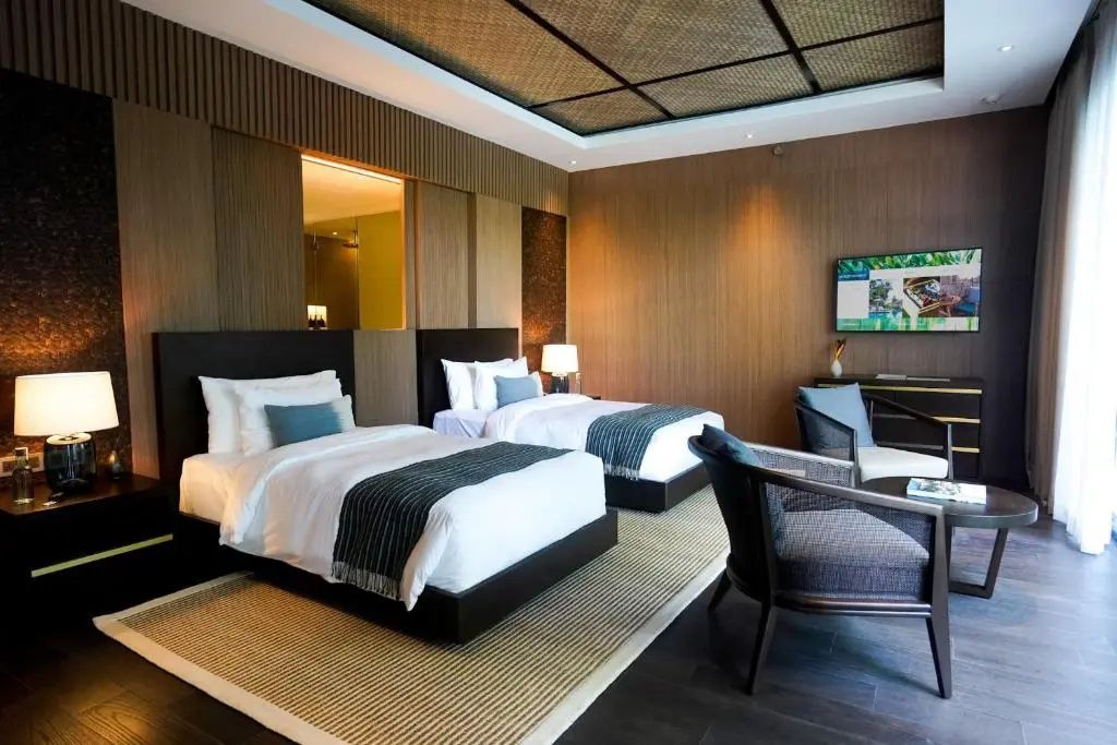 Hotelzimmer mit zwei Einzelbetten, Holzverkleidung und geflochtener Decke.