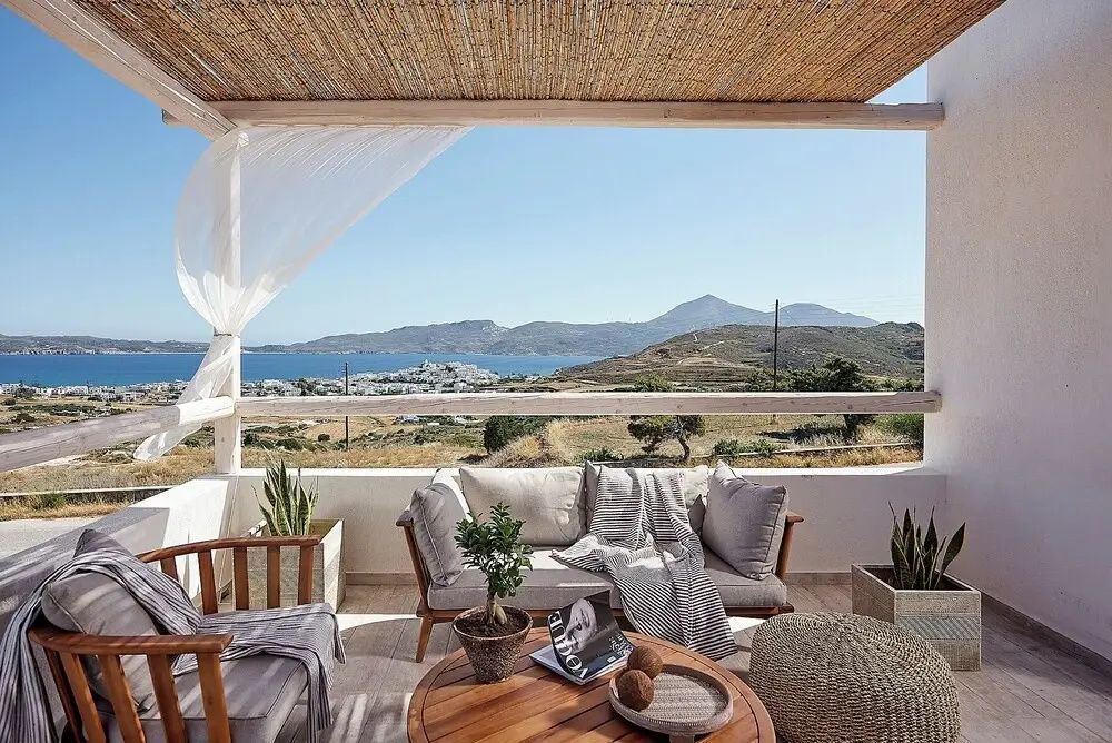 Überdachte Terrasse mit Polstermöbeln und freiem Blick auf das Meer und die Landschaft.