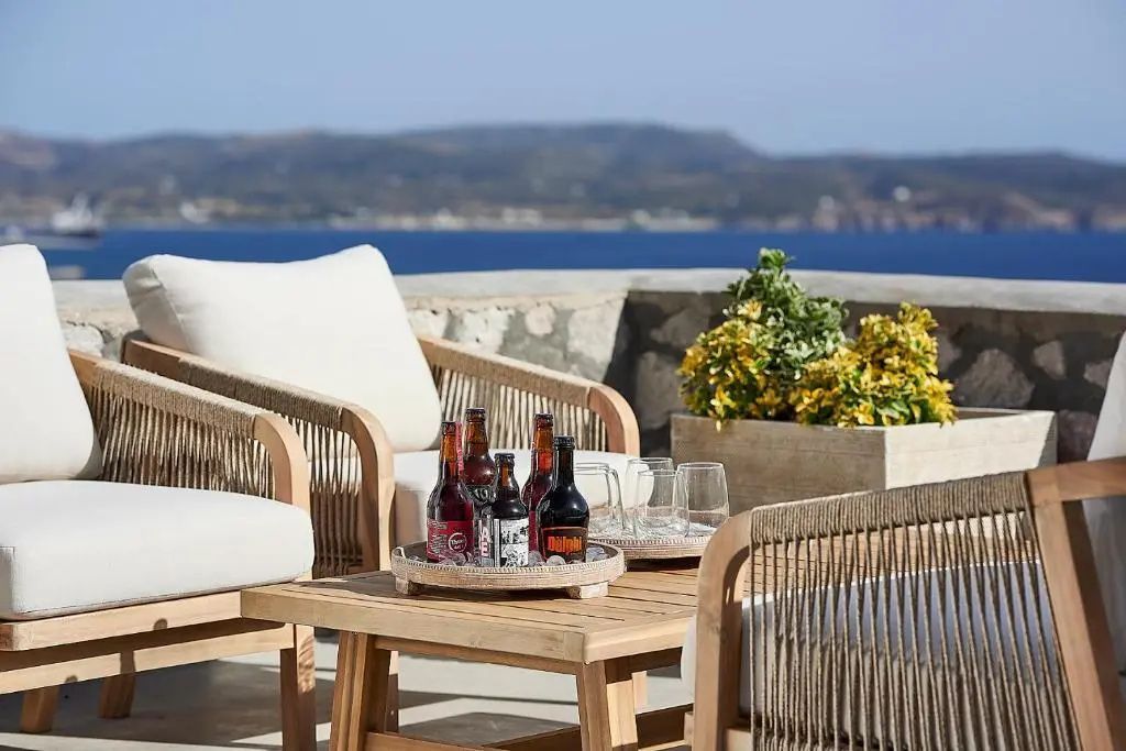 Terrassenmöbel aus Holz mit Getränken auf dem Tisch vor Kulisse der blauen Meeresbucht